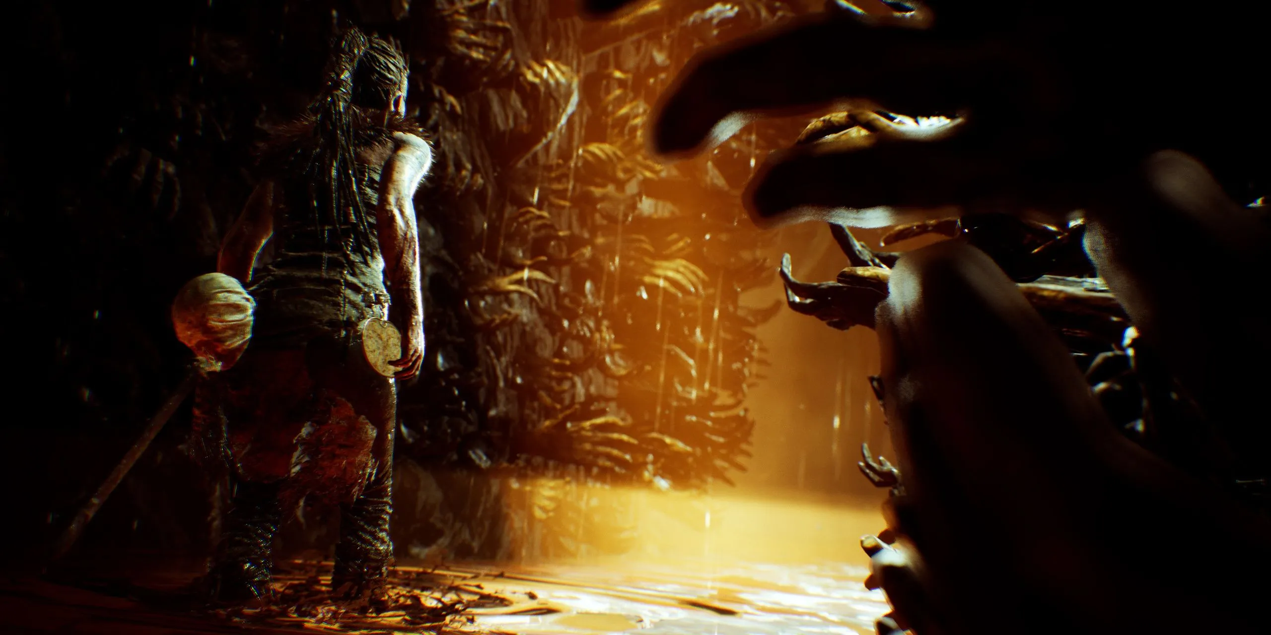 Senua đứng trước bức tường tay trong Hellblade: Senua's Sacrifice, mô tả trải nghiệm tâm lý phức tạp của nhân vật.